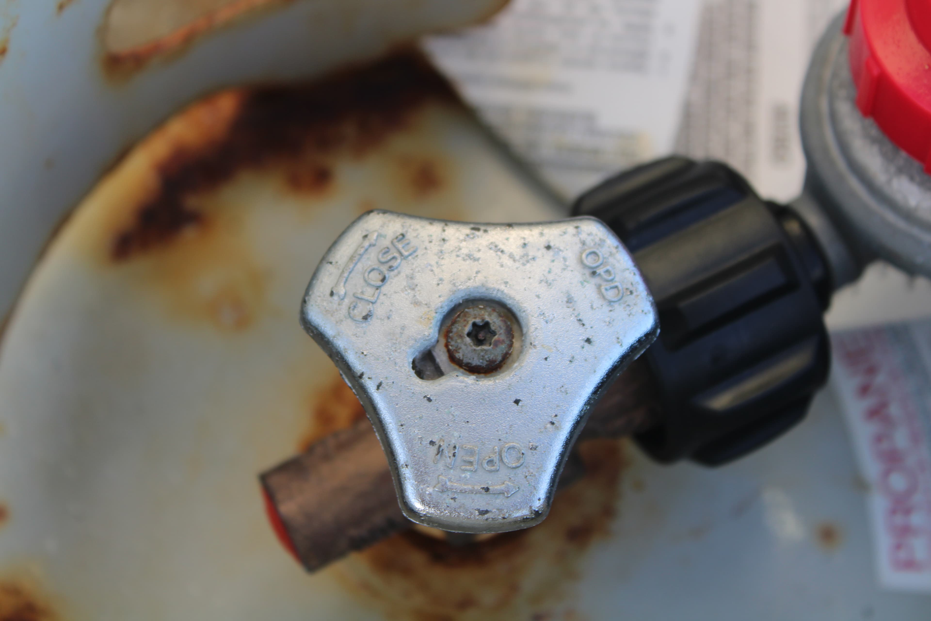 Close-up of the propane tank valve showing OPEN and CLOSE markings