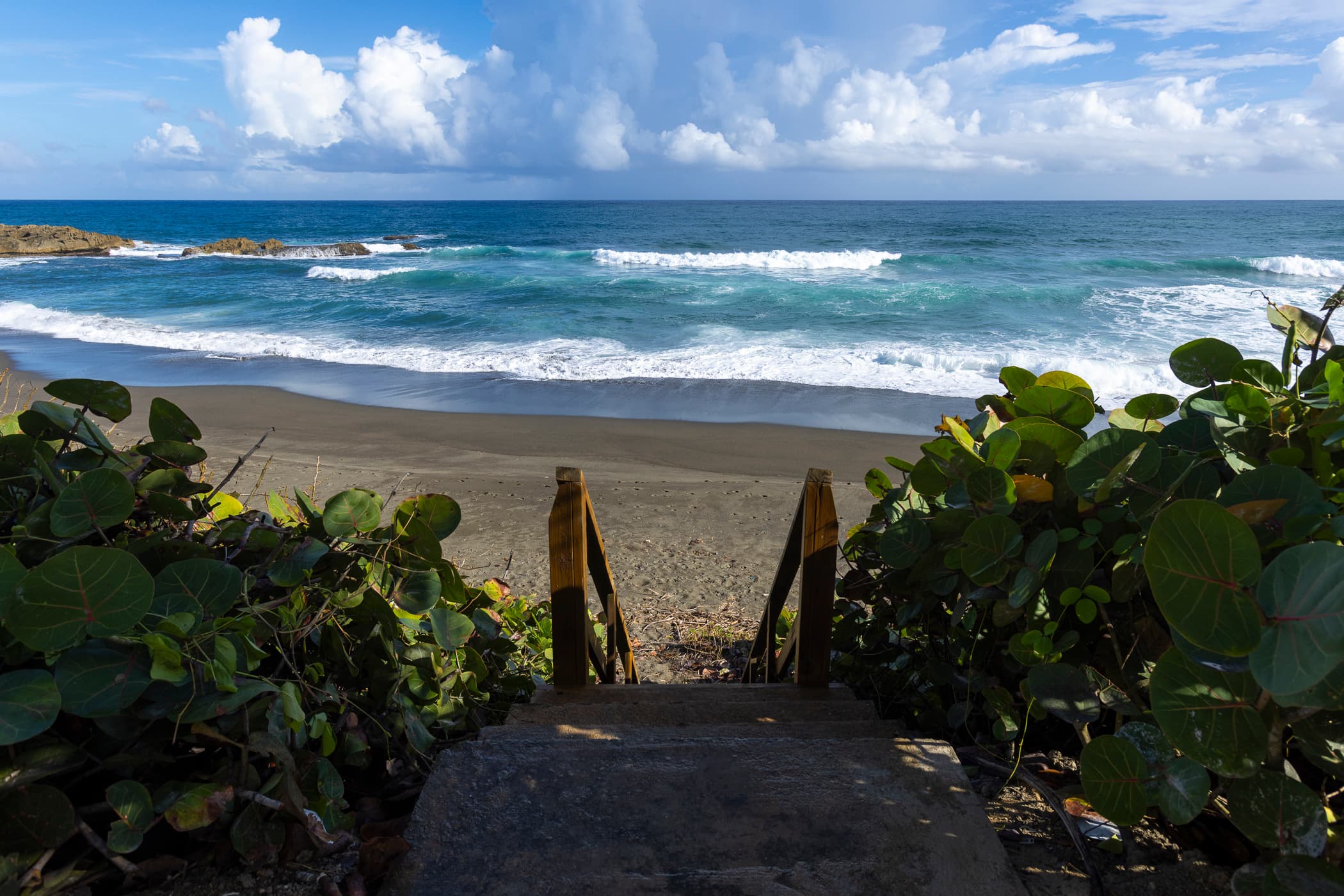 Private stairs leading down to the black-sand beach