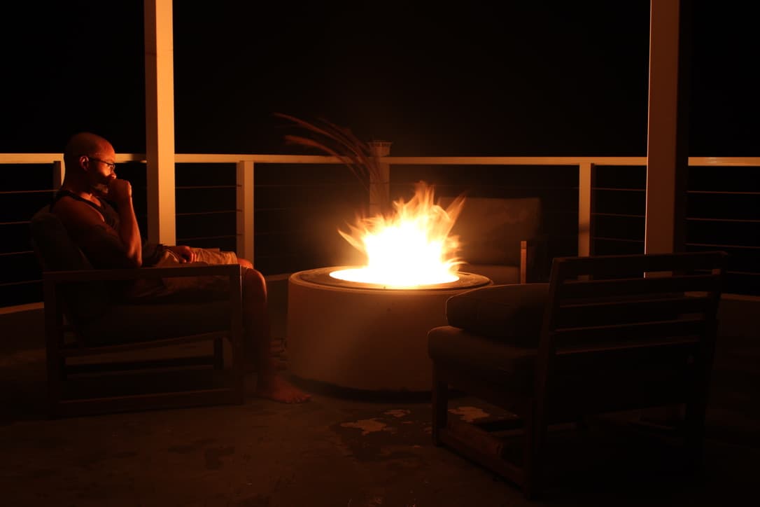 Ramon sitting beside the rooftop fire pit at night, surrounded by lounge chairs
